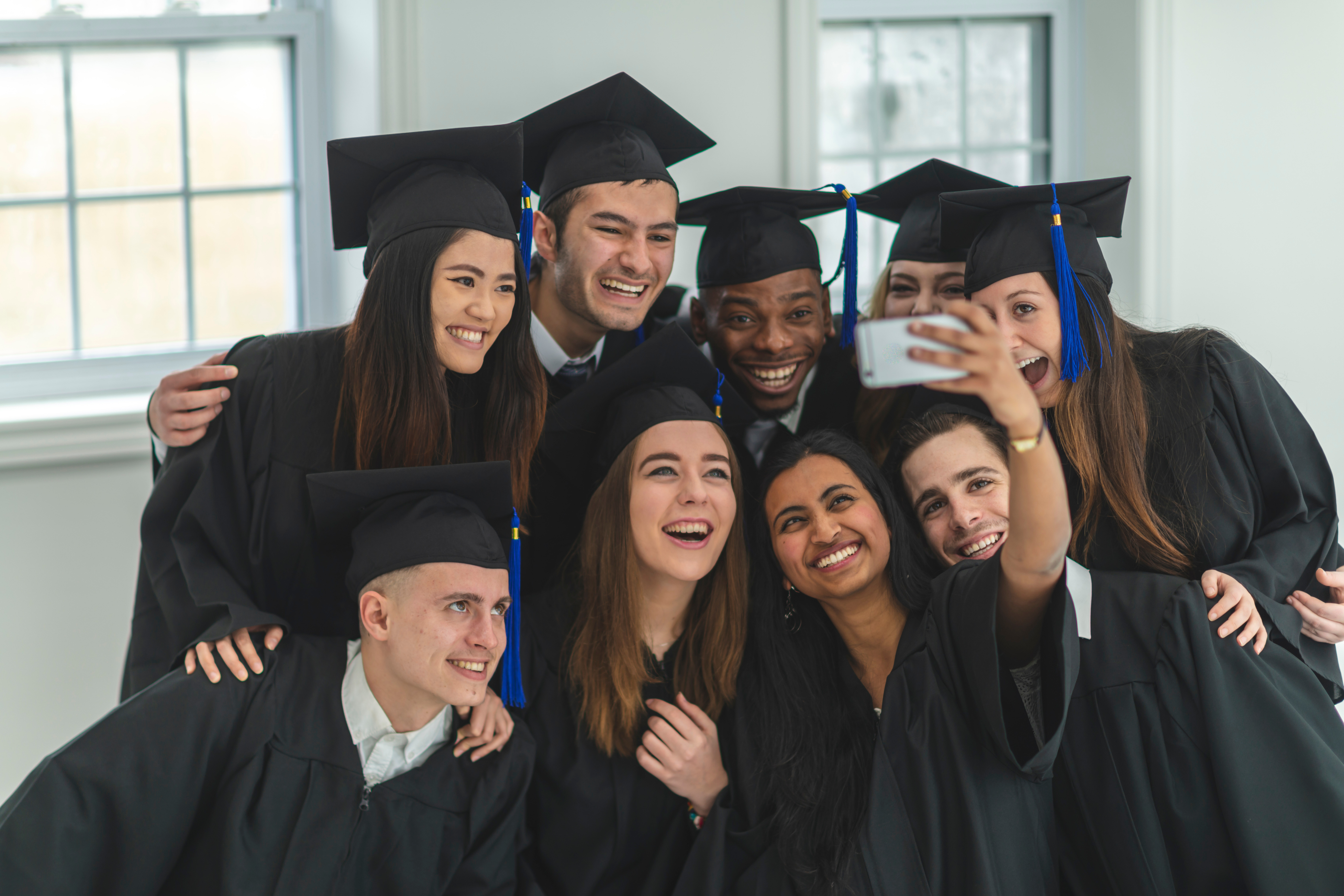 Nine happy college students in their cap and gown for graduation taking a selfie together. ERP software for education can help education institutions operate smoothly and help students succeed.