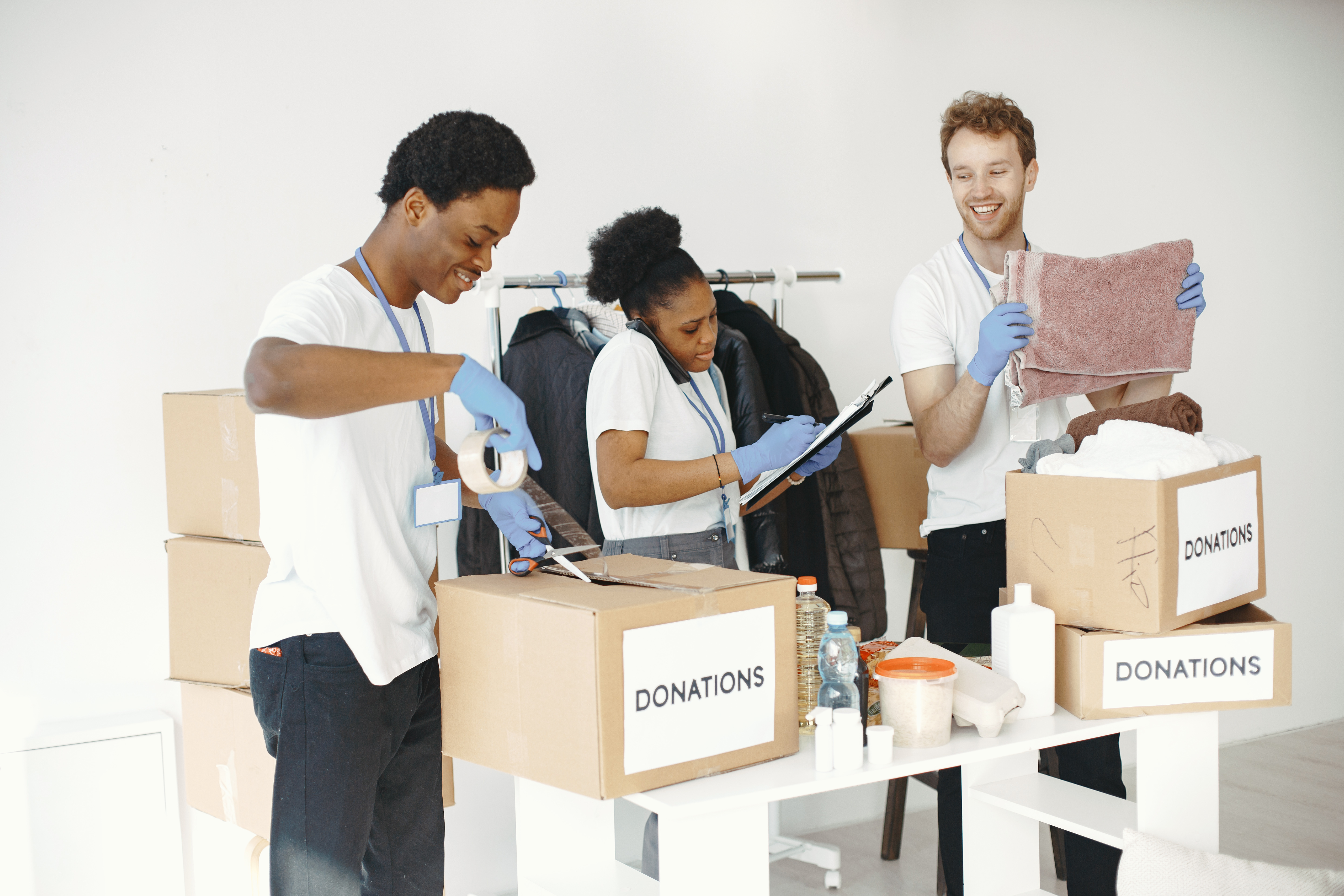 Three nonprofit volunteers assist in sorting through donations, tracking the items on a clipboard, and taping shut boxes full of ready-to-go donations. ERP software can help the nonprofit as a whole be empowered with streamlined processes.