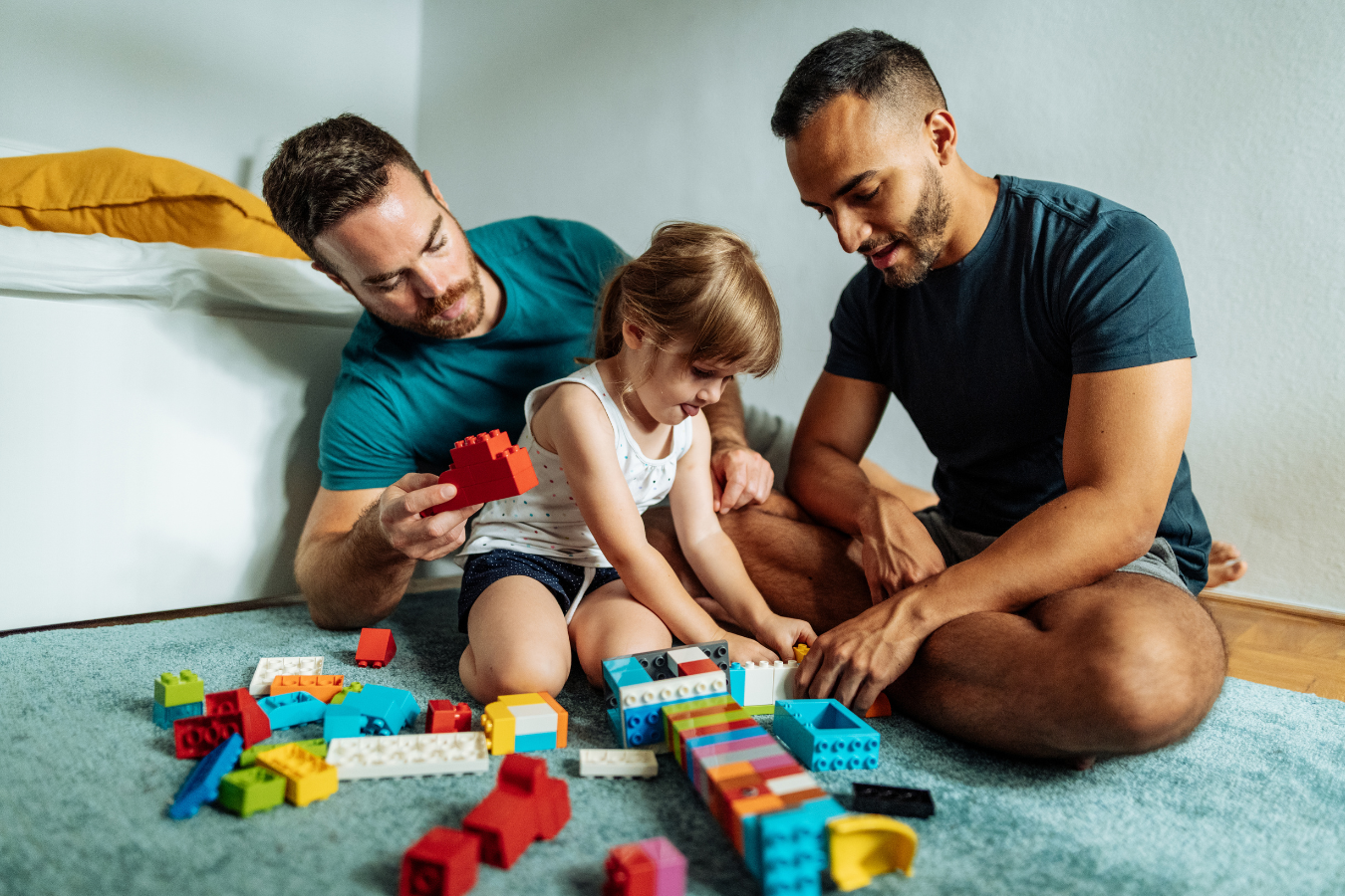 Two Dads play blocks with their adopted daughter. Sparkrock's ERP can help facilitate the adoption process by bridging technology and service together.