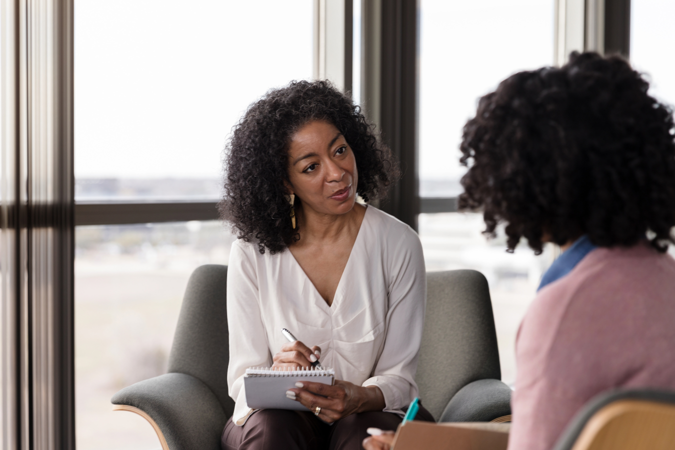 A mental health professional speaks with a client while writing down in her notebook. Mental health-focused ERP software can help promote care in mental health practice facilities.