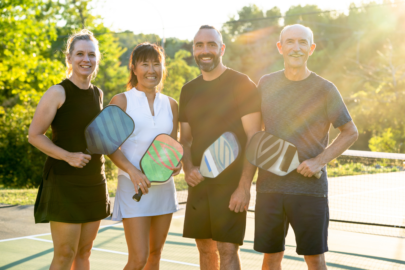 Two adult women and two adult men stand together for a picture before their pickleball game. In the article, it is mentioned that Pickleball Canada needed to work to streamline their policies, which could be assisted by an ERP like Sparkrock 365.