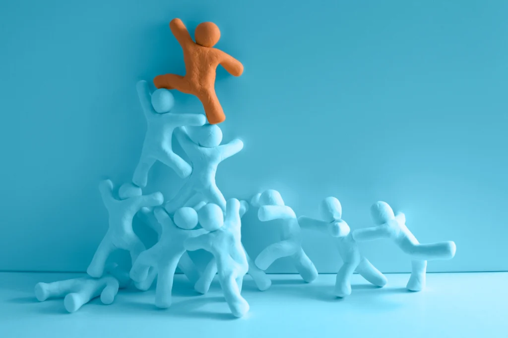 Clay figures working together to lift one leader higher, symbolizing nonprofit teamwork and empowerment.
