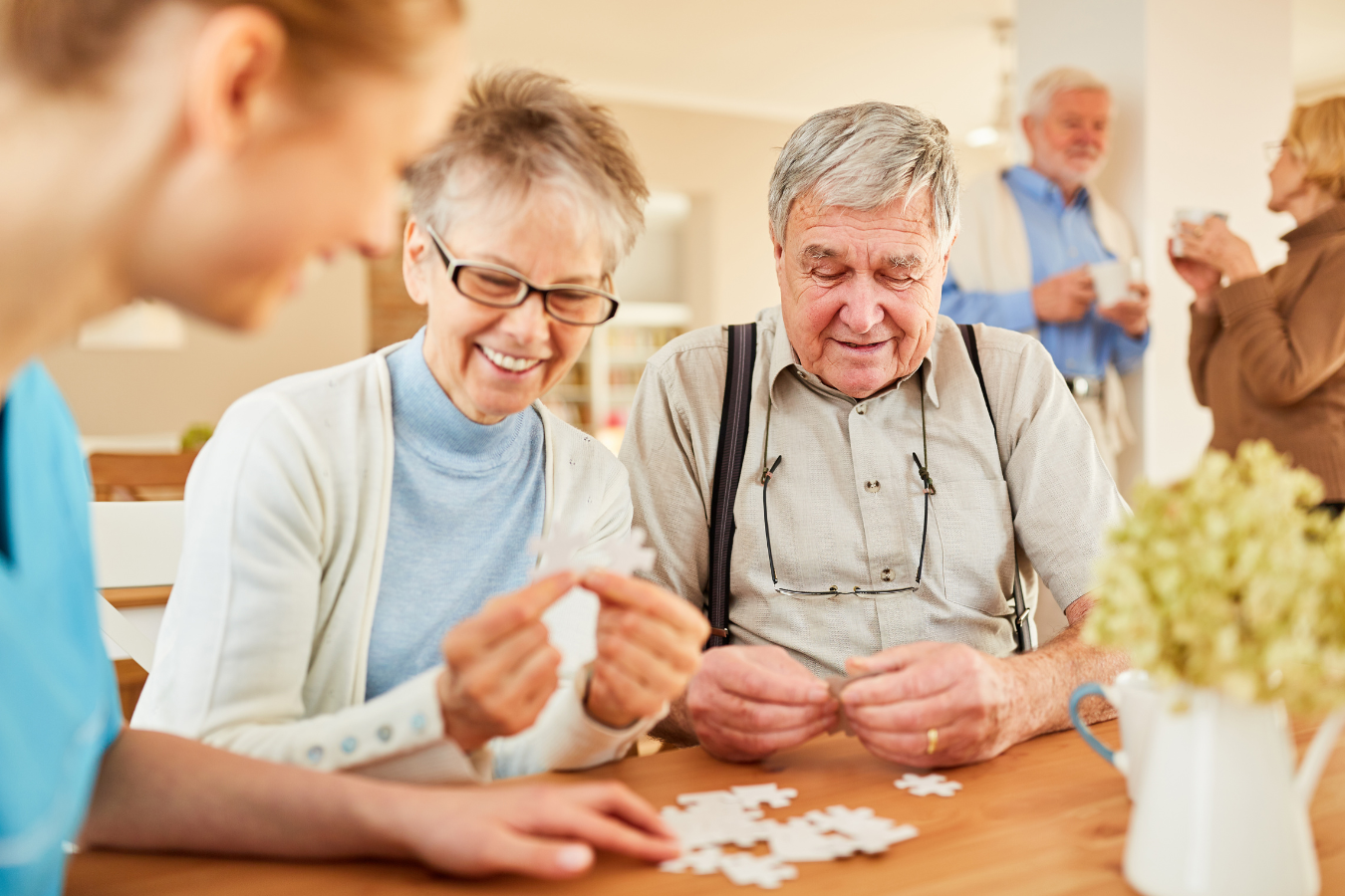 A healthcare professional helping two seniors with a puzzle at a senior citizen charity. Sparkrock 365 ERP supports senior citizen charities, optimizing efficiency for enhanced care and assistance.