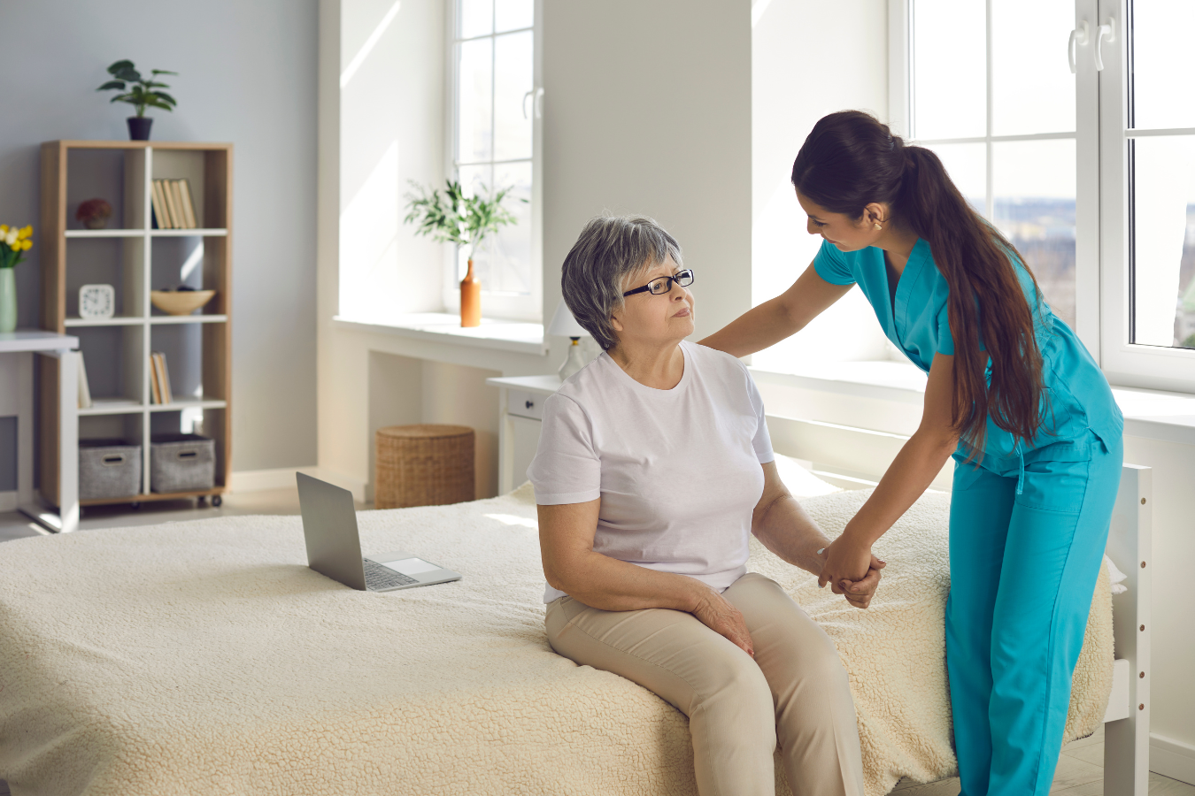 A health care professional assists and older woman in her bedroom in a residential care home.