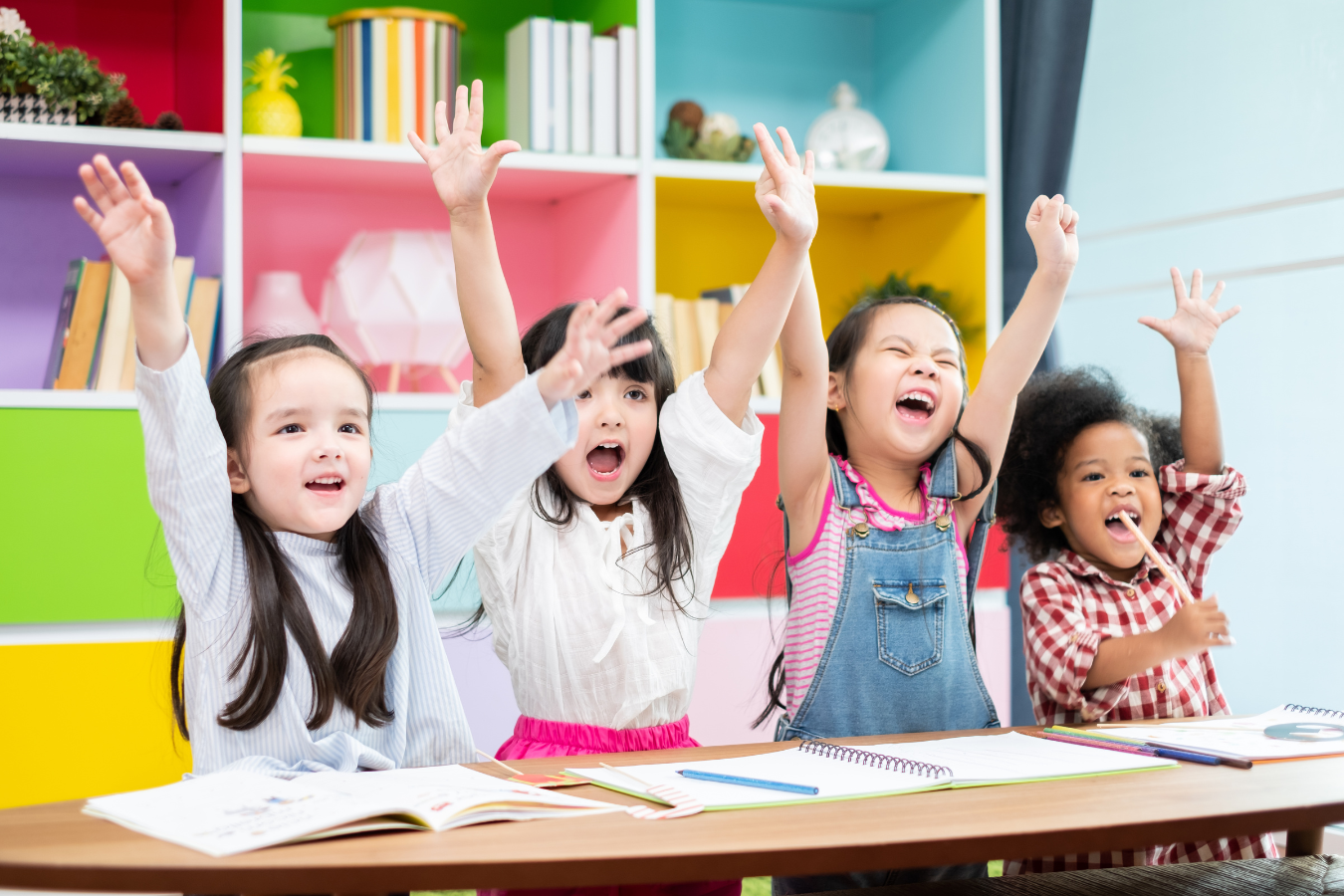 Four students raise their hands in the air with glee. Administrators who use education ERPs with AI can spend more time focusing on student engagement.