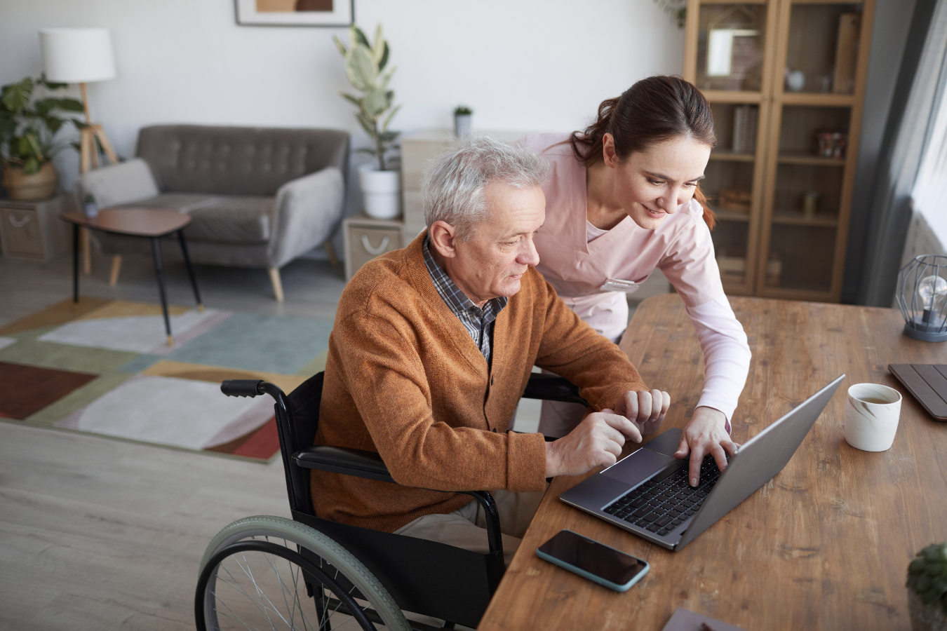 A female nurse helps an older man in a wheelchair work on his computer. ERP solutions can integrate tools like PowerBI to help health and human services to do what they do best - focus on their patients and clientele.