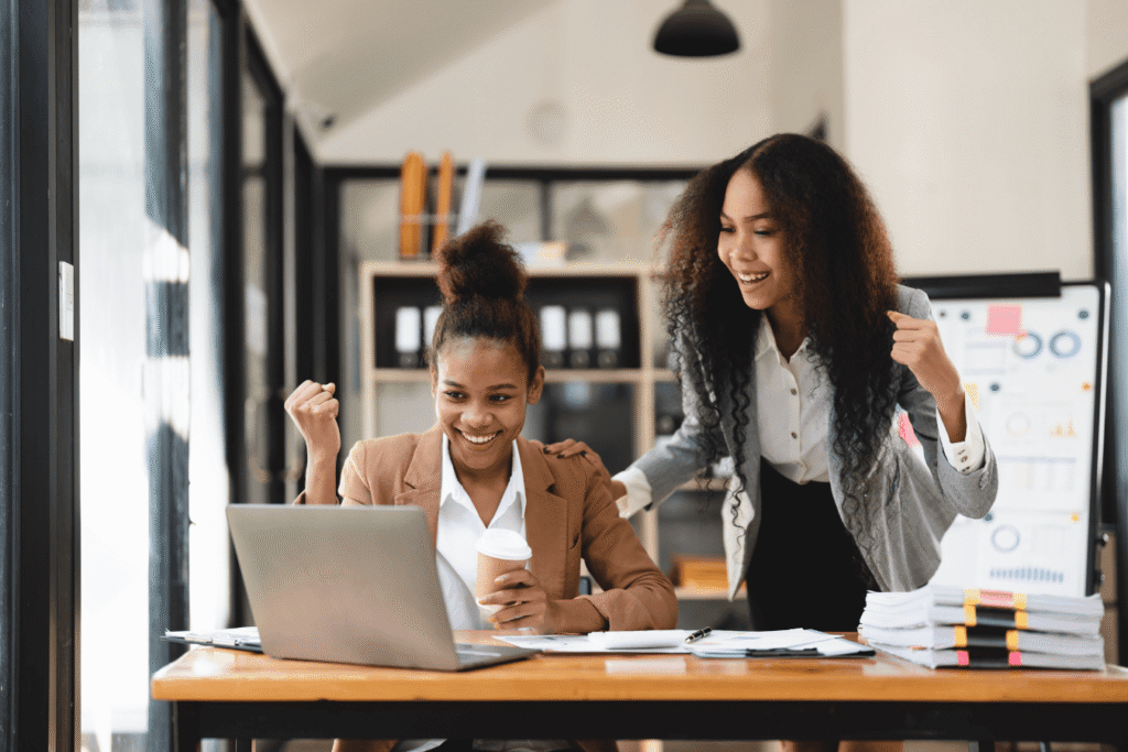 Two female staff are excited while looking at a computer.