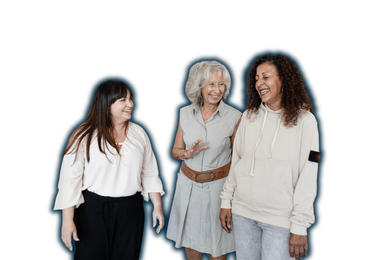 Three diverse women of different ages standing and smiling together, representing a joyful and inclusive group of volunteers.