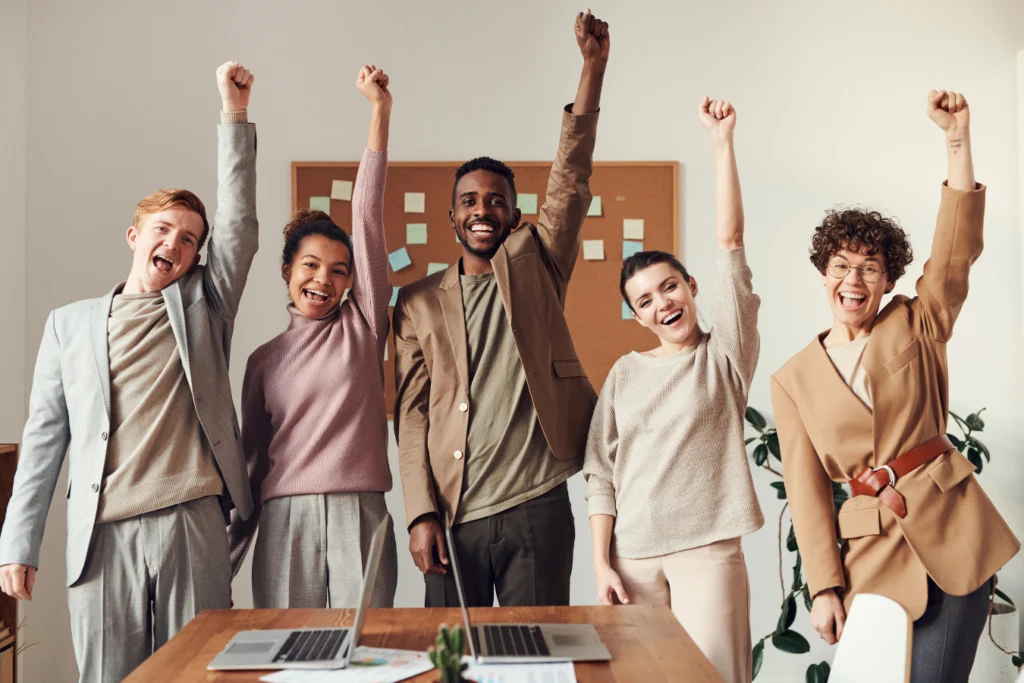 Group of nonprofit professionals raising their arms in celebration, symbolizing teamwork, success, and effective expense management.