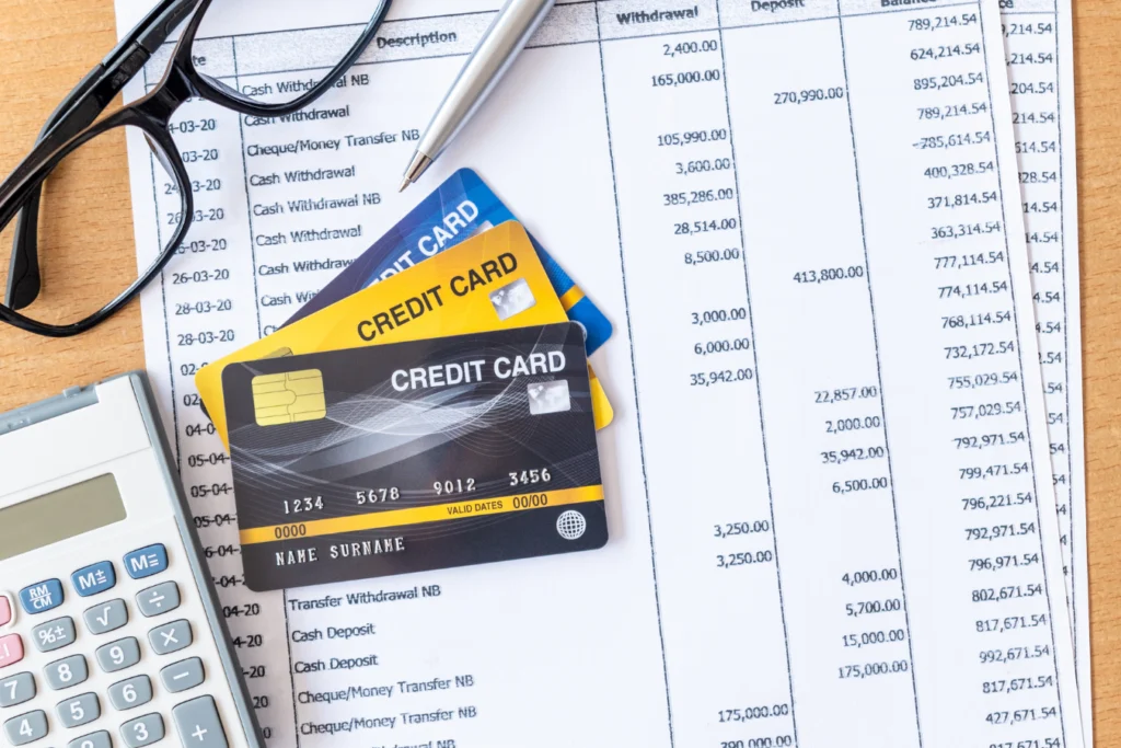 Stack of credit cards on top of a financial statement with calculator, glasses, and pen, symbolizing nonprofit credit card reconciliation.