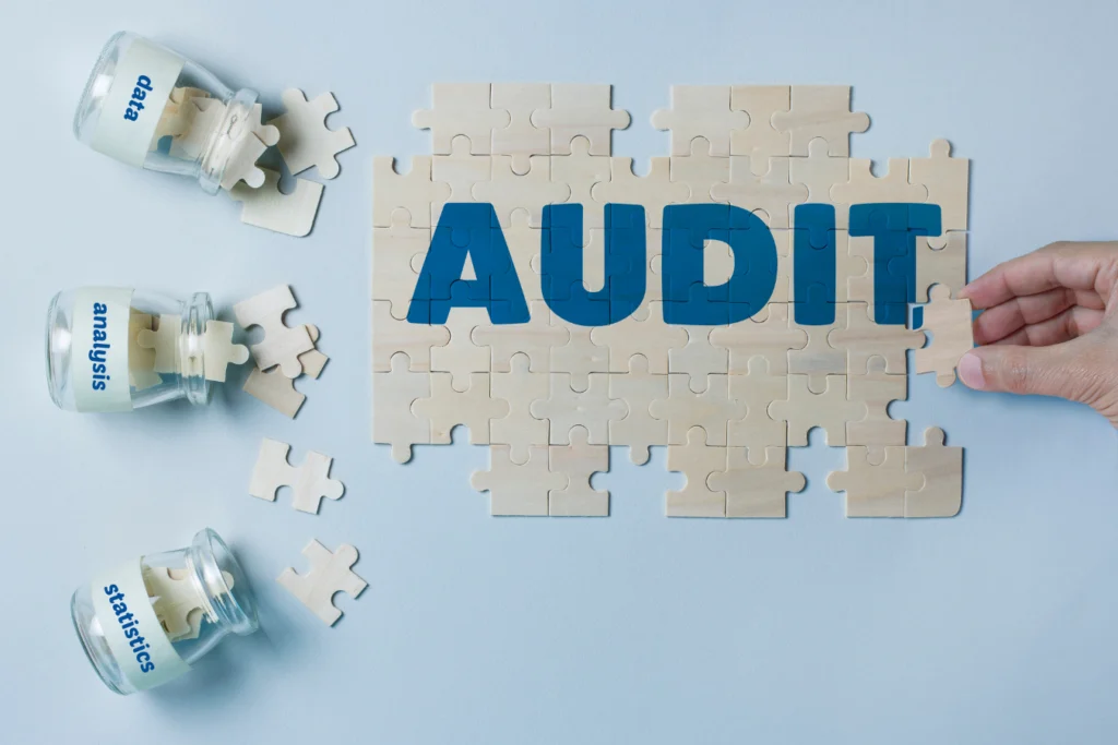 Hand placing puzzle pieces together with the word “AUDIT,” symbolizing how data, analysis, and reporting fit together in nonprofit audits