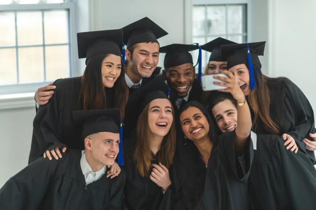 Group of college graduates in caps and gowns smiling and taking a selfie together, representing the positive outcomes of efficient education management.