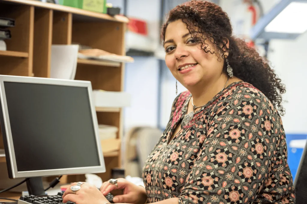 School secretary working at a computer, efficiently managing school finances and operations with Sparkrock's K12 ERP software.