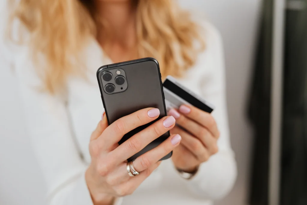Parent making a cashless school payment on a smartphone with a credit card, representing digital payment systems for schools