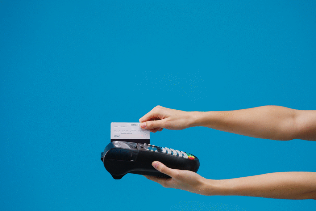 Hand inserting a credit card into a payment terminal against a blue background, representing payment processing in activity fund software.