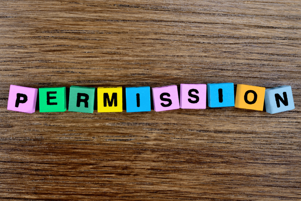 Colorful wooden letter tiles spelling 'PERMISSION' on a wood grain background, representing permission slip and forms software for schools.
